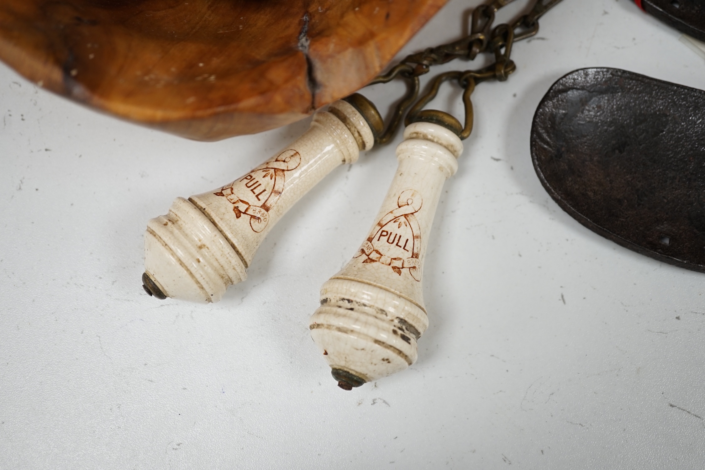 A cast iron toy model of a tricycle, a carved wooden bow, a classical figurative door knocker, a pair of metal cow shoes and two ceramic cistern pulls, bowl 30cm diameter. Condition - fair